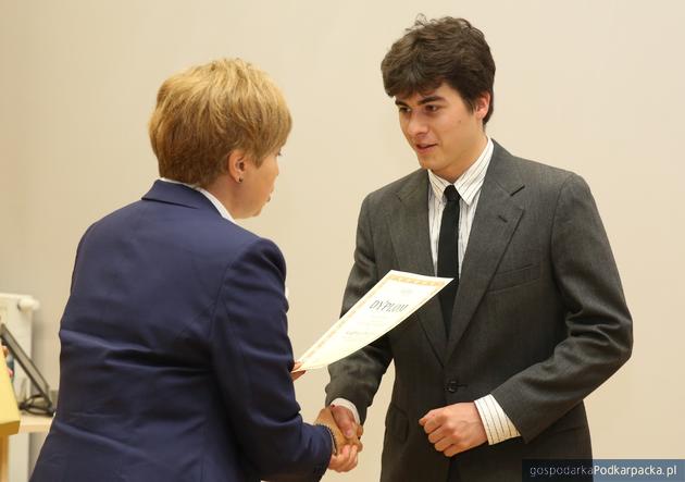 Piotr Pręga dostaje dyplom i nagrodę od wiceprezes Barbary Kostyry