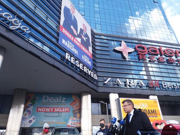 Poseł Marcin Warchoł podczas konferencji prasowej przed Galerią Rzeszów. Powyżej baner z Tadeuszem Ferencem